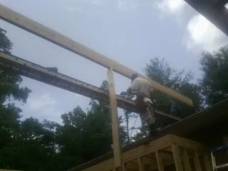 Carpenter setting a ridge beam over a new addition frame — Ice Dam Removal by Roofing Brothers in Wiggins