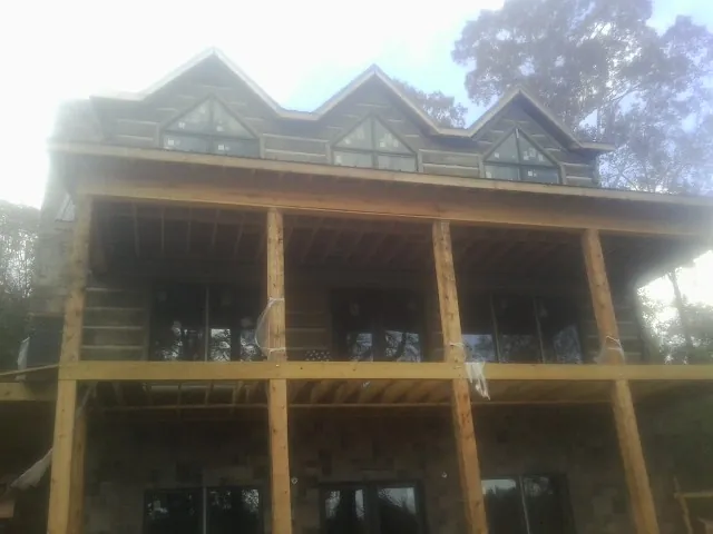 Dormers and porch framing on a large log home under construction — Roof Coating work by our crew in Wiggins